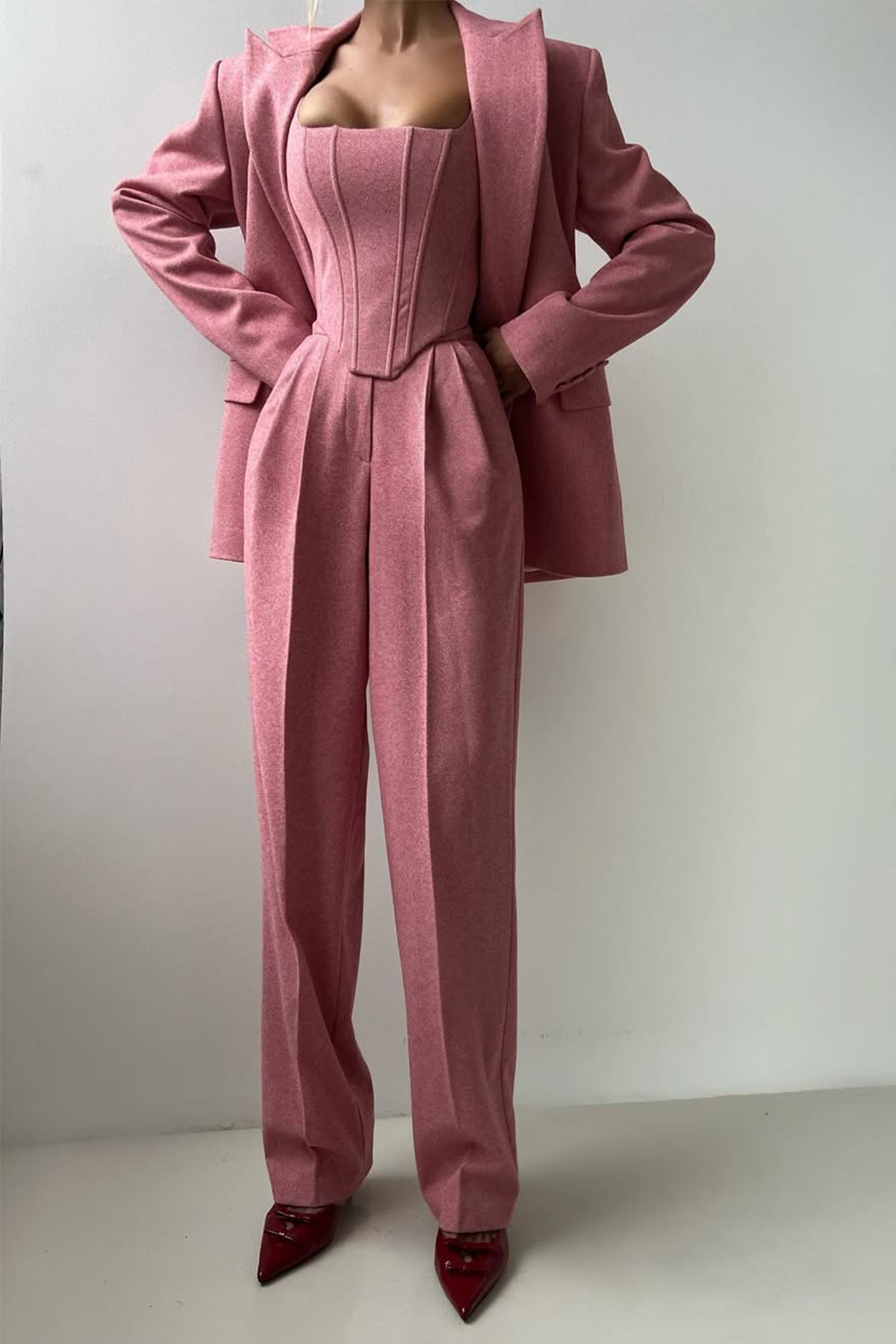 "Elegant women's three-piece suit with structured blazer, bustier top, and wide-leg trousers in classic herringbone weave."