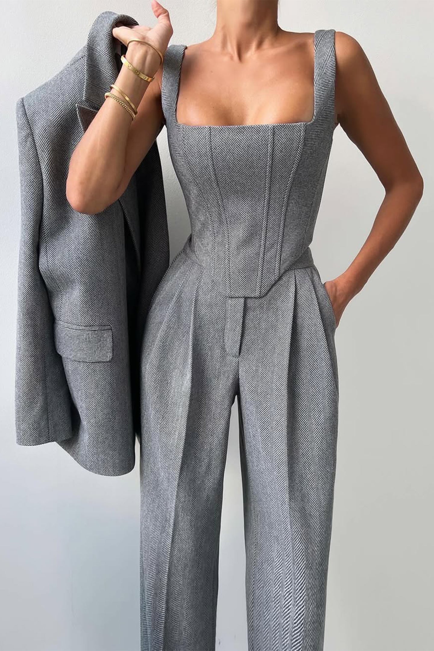 "Elegant women's three-piece suit with structured blazer, bustier top, and wide-leg trousers in classic herringbone weave."
