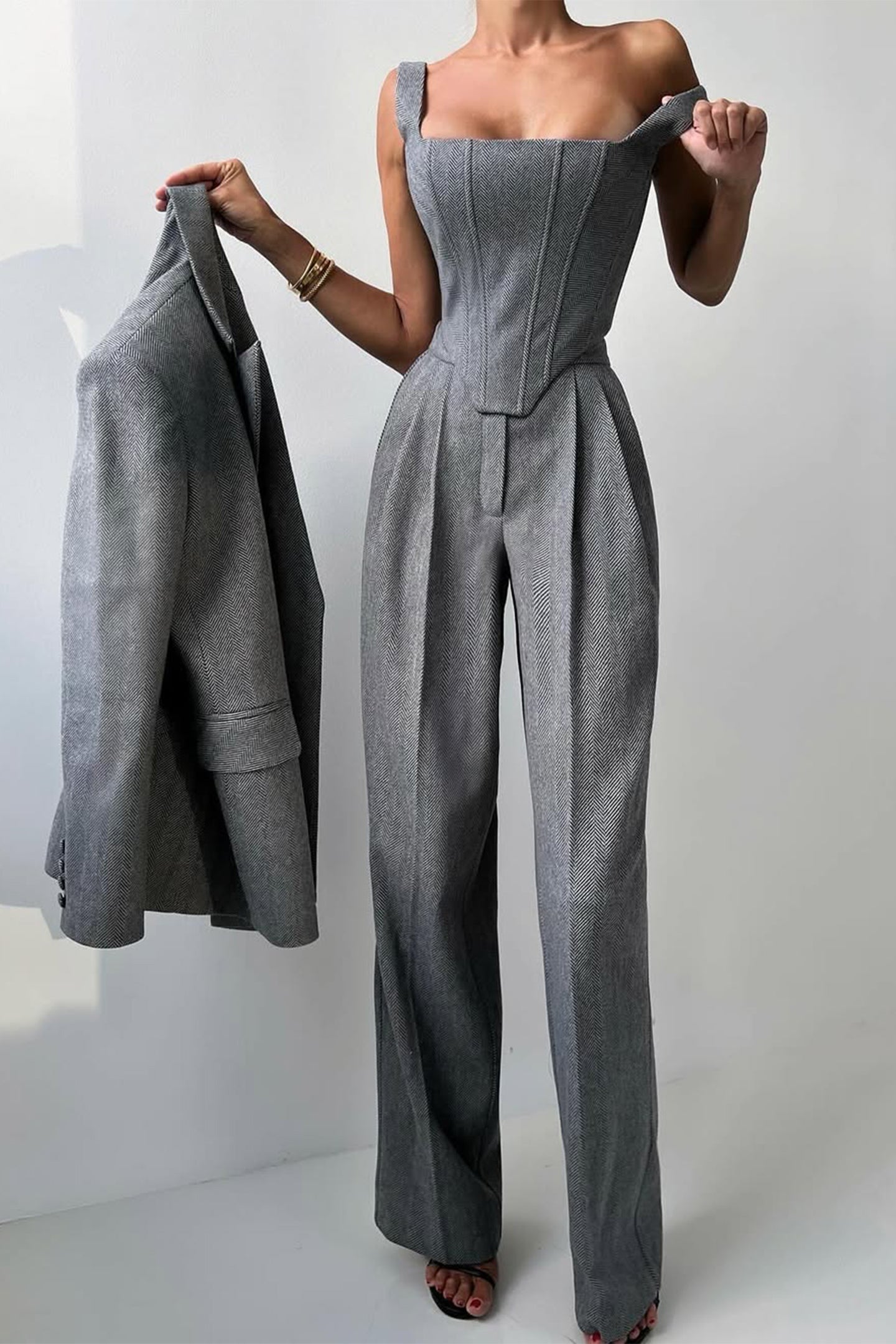 "Elegant women's three-piece suit with structured blazer, bustier top, and wide-leg trousers in classic herringbone weave."