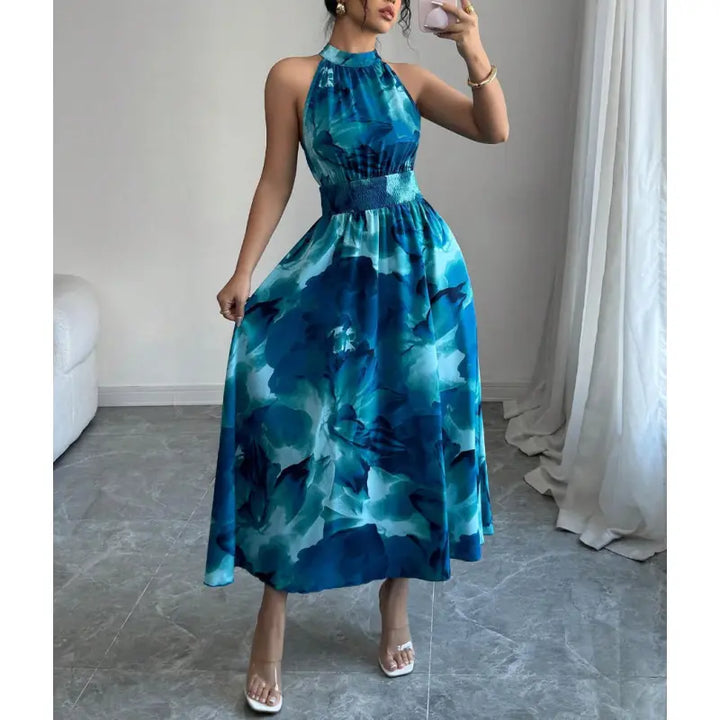 Flowy women's halter neck maxi dress with smocked waist & abstract design, ideal for casual summer wear in blue.