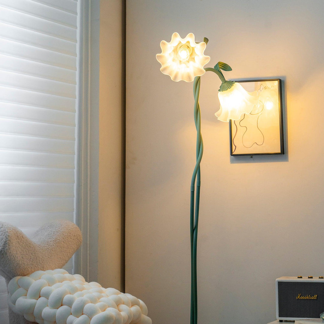 Green botanical floor lamp, detailed floral elements, white shade, modern living room.