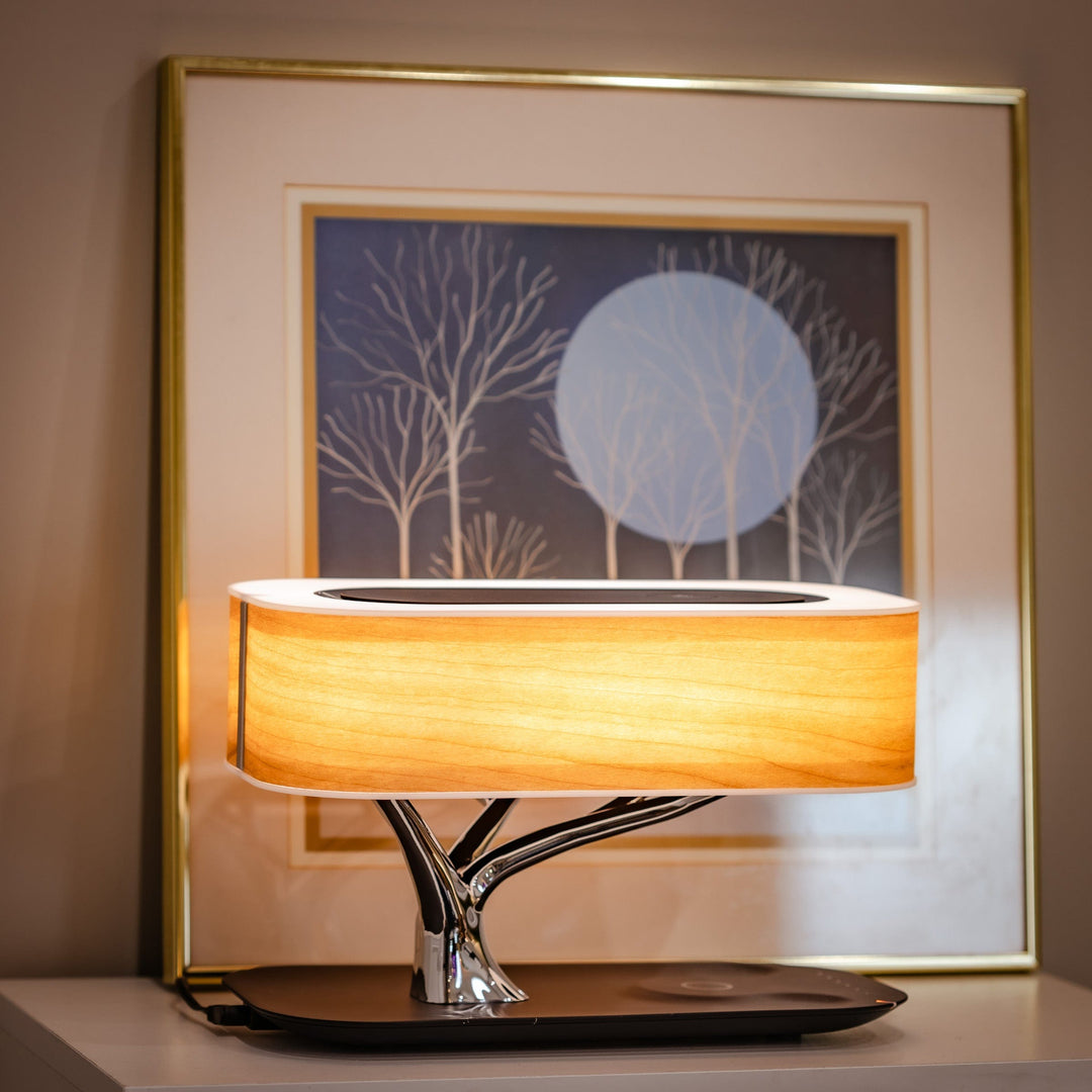 Minimalist modern LED lamp providing wireless phone charging and a Bluetooth speaker for ultimate convenience.