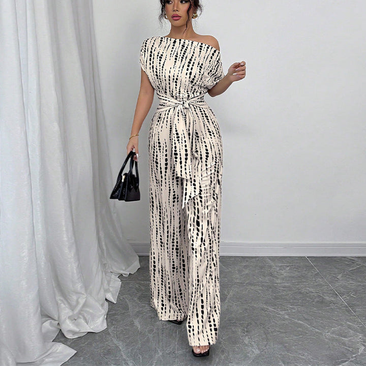 Modern white printed wide leg jumpsuit for women. Features one shoulder and a belted waist, a true fashion statement piece.
