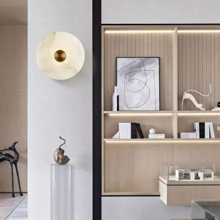 Alabaster shade round brass LED wall sconce, a sophisticated lighting fixture for modern home interiors.