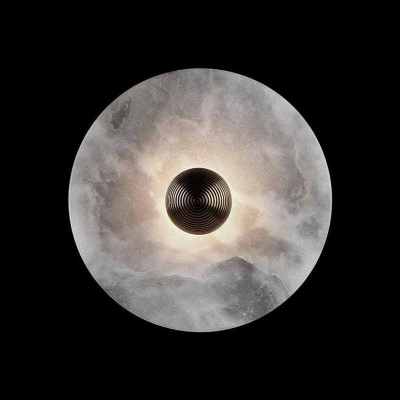 Luxury round brass LED wall sconce with alabaster shade. A modern lighting fixture for ambient home decor.