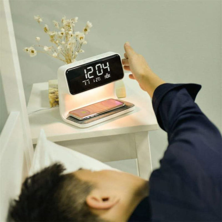 Multifunction bedside lamp with dimmable LED light, digital alarm clock & integrated wireless phone charger.