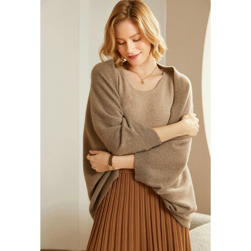 Woman wearing a beige knit shawl wrap, showcasing its elegant drape and warmth.