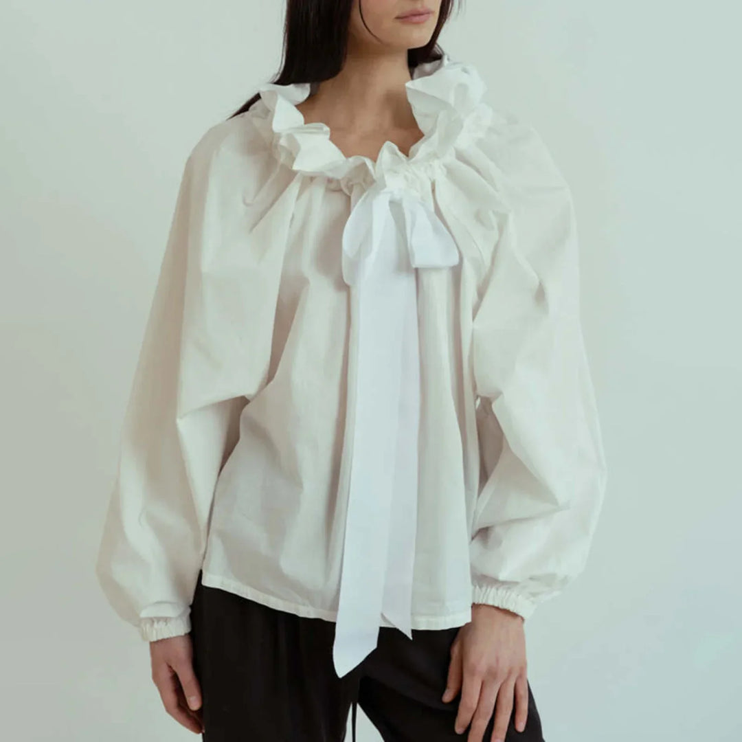 Versatile white women's top, combining elegance with fashion in puffed lantern sleeves and bow tie.