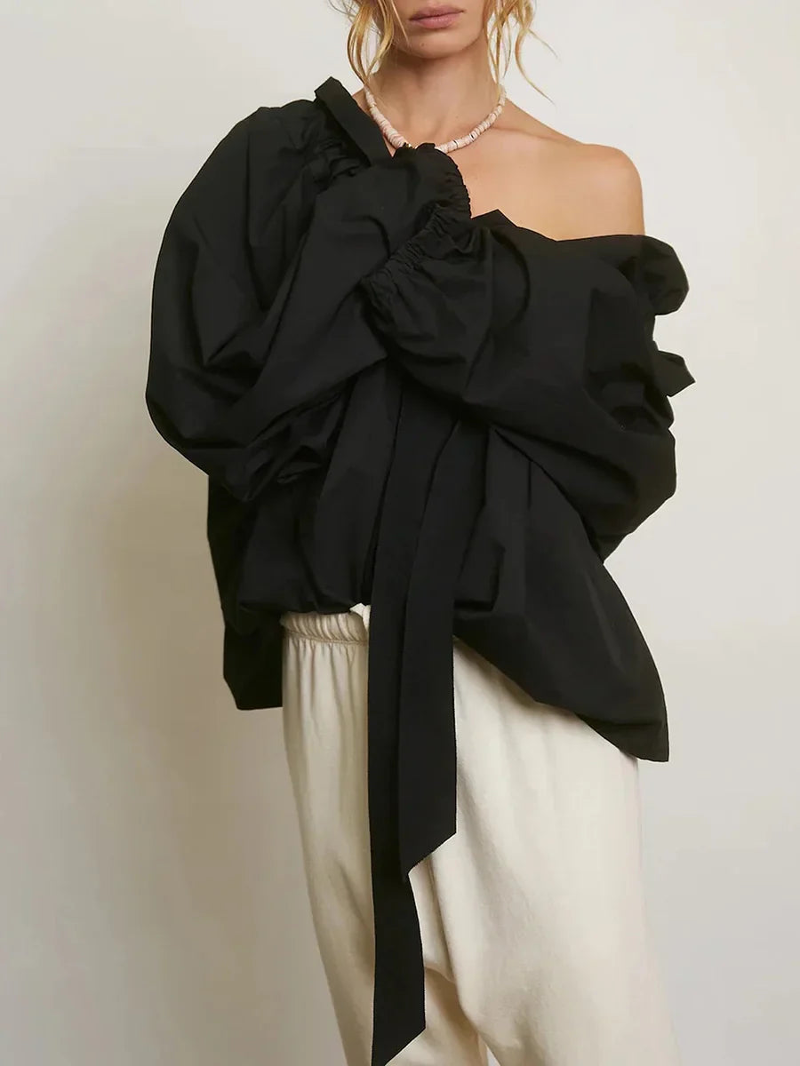 Close-up of the ruffled neck and bow tie on an elegant white women's top with puffed lantern sleeves.