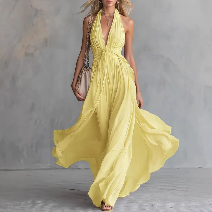 Women's formal backless maxi dress. Features a graceful flowy pleated skirt & elegant halter neckline.