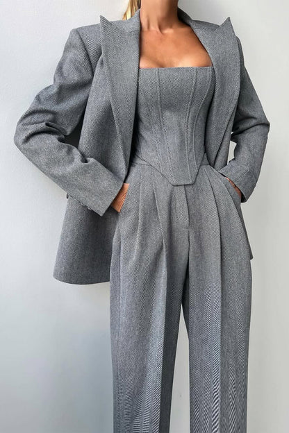 "Elegant women's three-piece suit with structured blazer, bustier top, and wide-leg trousers in classic herringbone weave."