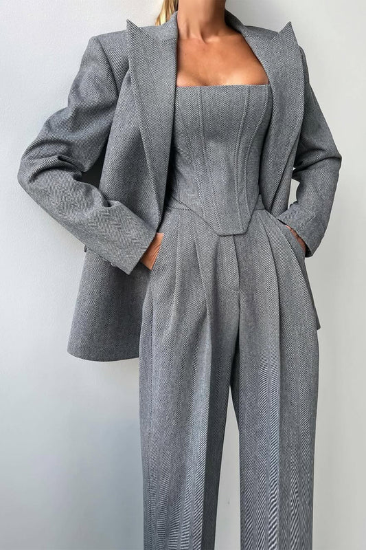 "Elegant women's three-piece suit with structured blazer, bustier top, and wide-leg trousers in classic herringbone weave."