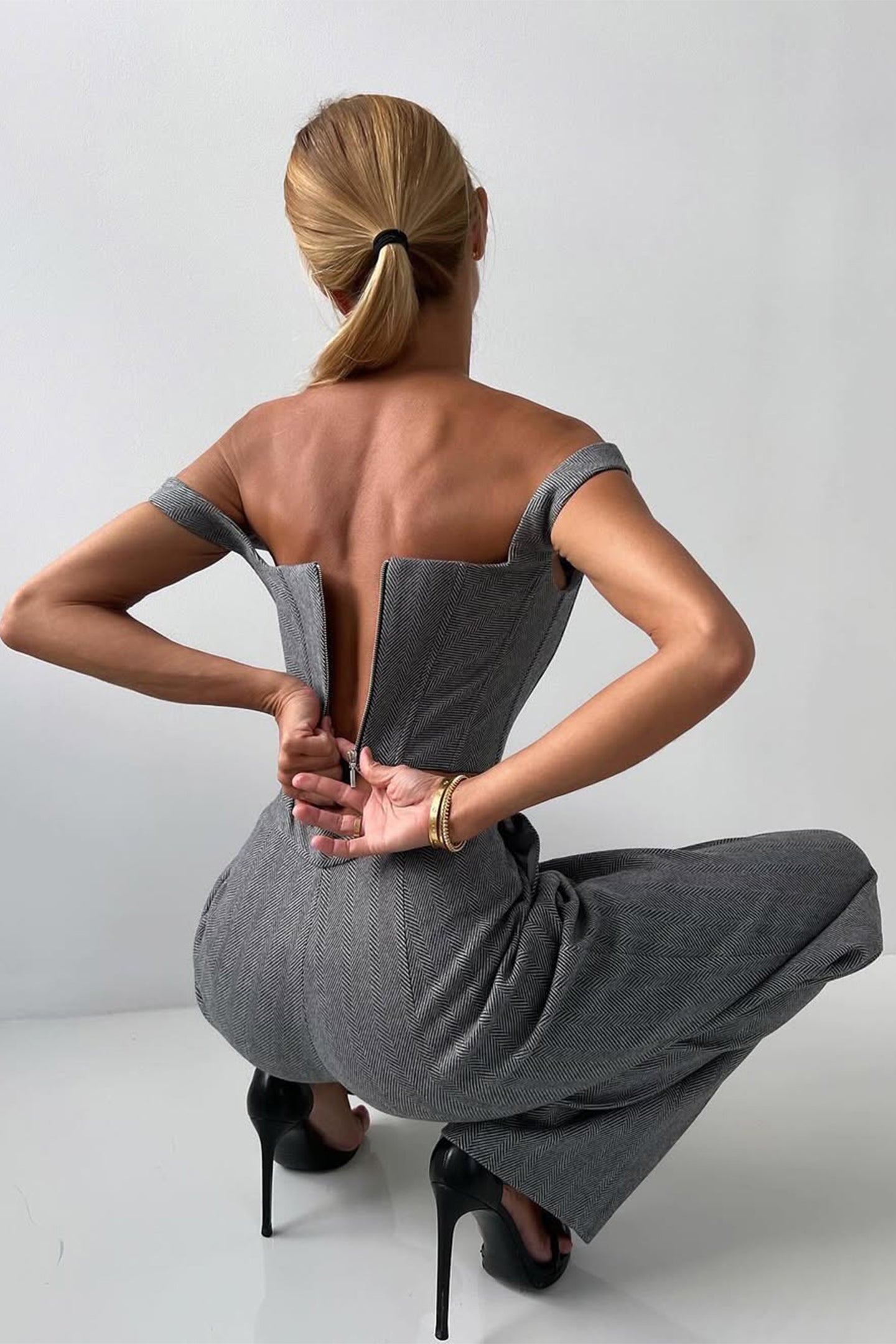 "Elegant women's three-piece suit with structured blazer, bustier top, and wide-leg trousers in classic herringbone weave."