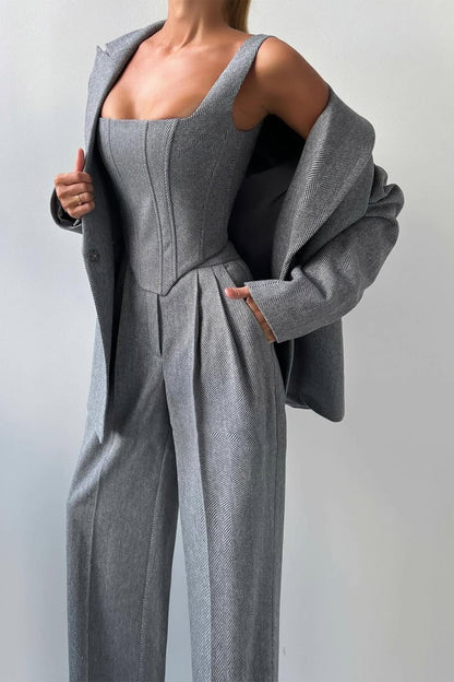 "Elegant women's three-piece suit with structured blazer, bustier top, and wide-leg trousers in classic herringbone weave."