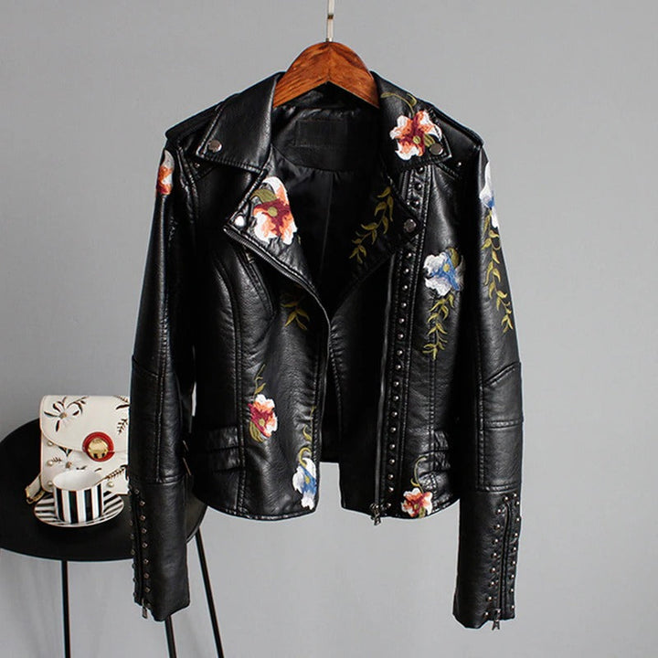 Stylish woman modeling an embroidered faux leather biker jacket with floral accents.