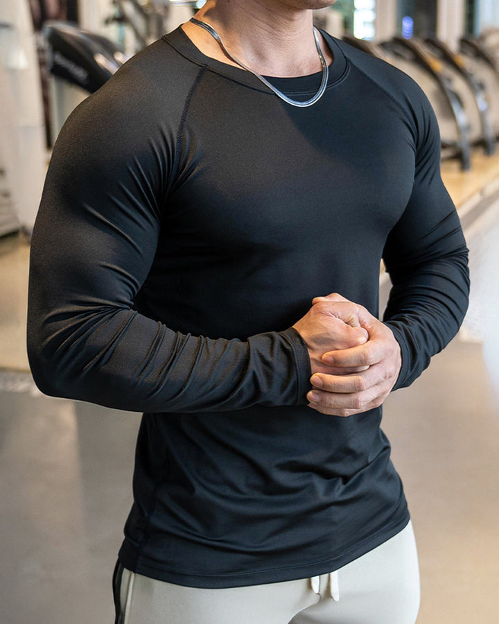 Model showcasing the stretch fabric of a black men's athletic shoulder cut long sleeve shirt