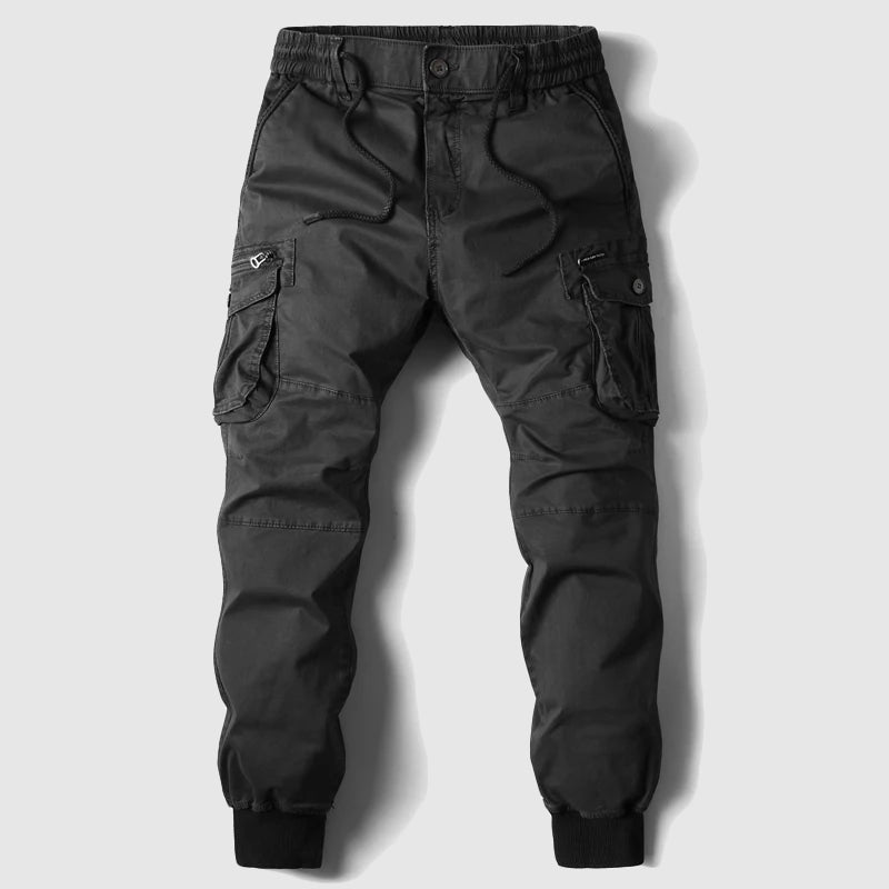 Stacked image of multiple men's cargo jogger pants in various colors: black, grey, khaki, and olive, emphasizing versatility.