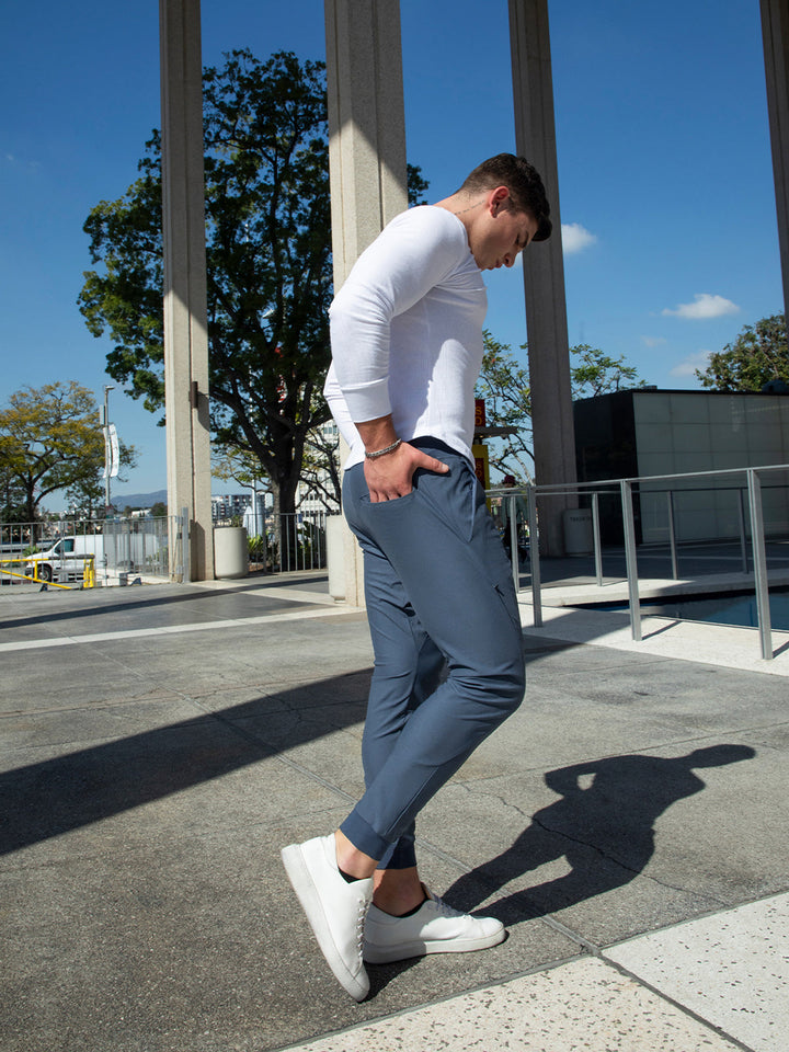 Man relaxing comfortably in men's performance joggers, modern fit, dark blue.