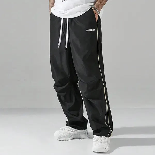 Men's relaxed fit black track pants made from nylon, perfect for athletic wear and casual comfort.