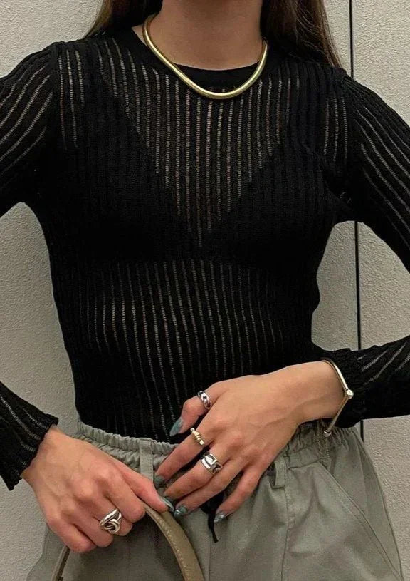 Model in black sheer ribbed long sleeve top for elegant party wear. Fitted & chic for a modern night out.