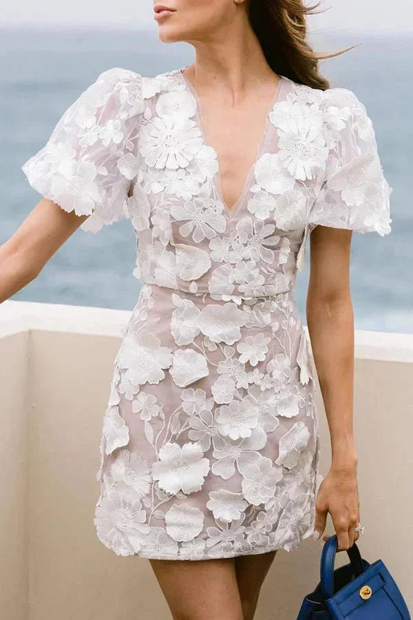 Feminine women's mini dress with vibrant 3D floral appliqué. Puff sleeves, V-neck. Great for elegant spring/summer events.