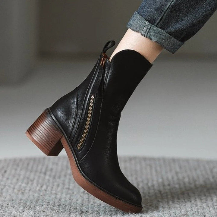 Front view of women's black leather ankle boots, emphasizing sleek design and zip detailing