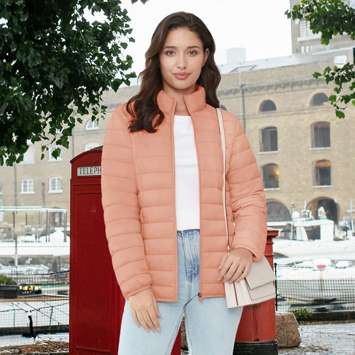 Lifestyle image: woman walking in a park, wearing a lightweight quilted puffer jacket. Fall fashion.
