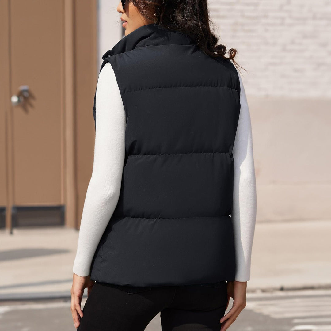 Women's navy puffer vest, quilted, zipper fully closed, showcasing its warm winter apparel fit