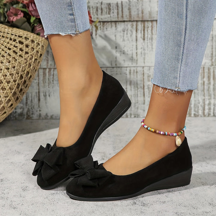 Chic women's ballet flats featuring a stylish bow and comfortable wedge heel.