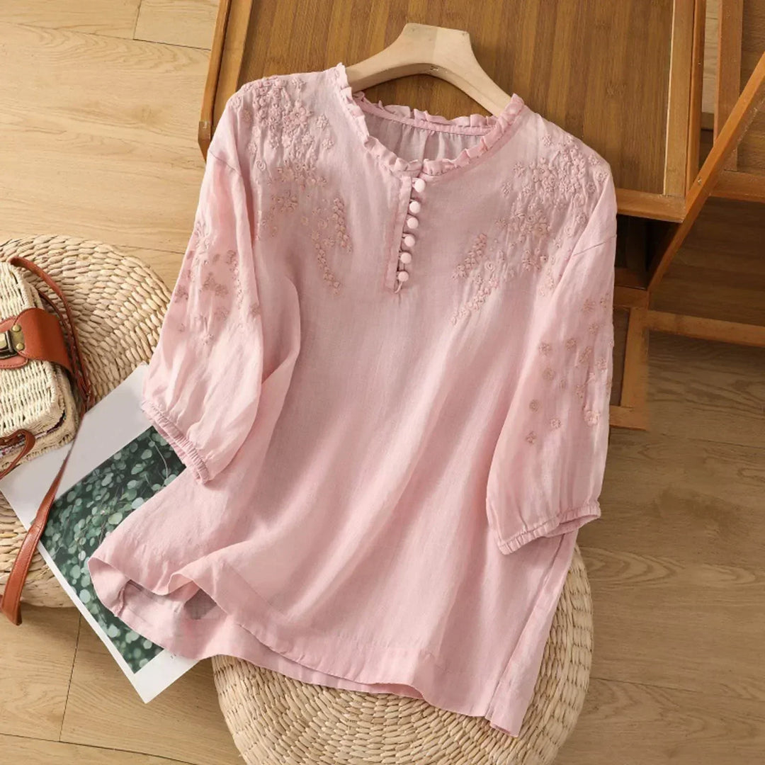 Close-up of elegant women's embroidered blouse, showcasing intricate vintage floral stitching on the chest.