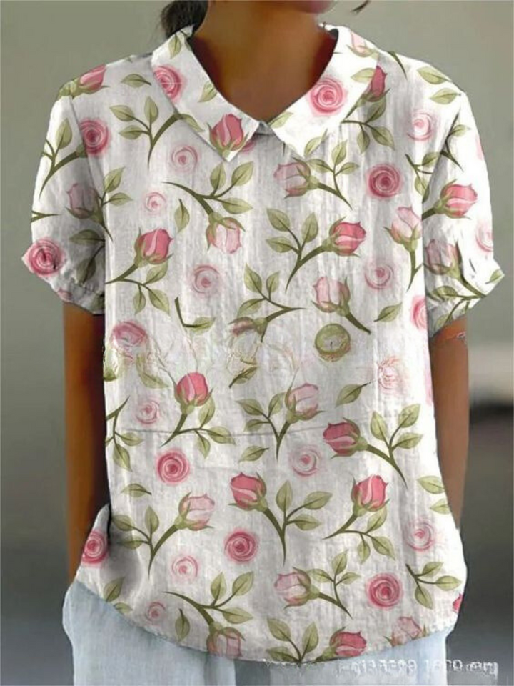 Close-up of women's short sleeve blouse showcasing intricate floral vine embroidery and Peter Pan collar.