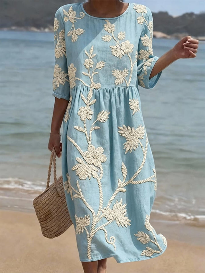 Women's floral embroidered flowing maxi dress. Elegant spring/summer style with three-quarter sleeves and round neck.