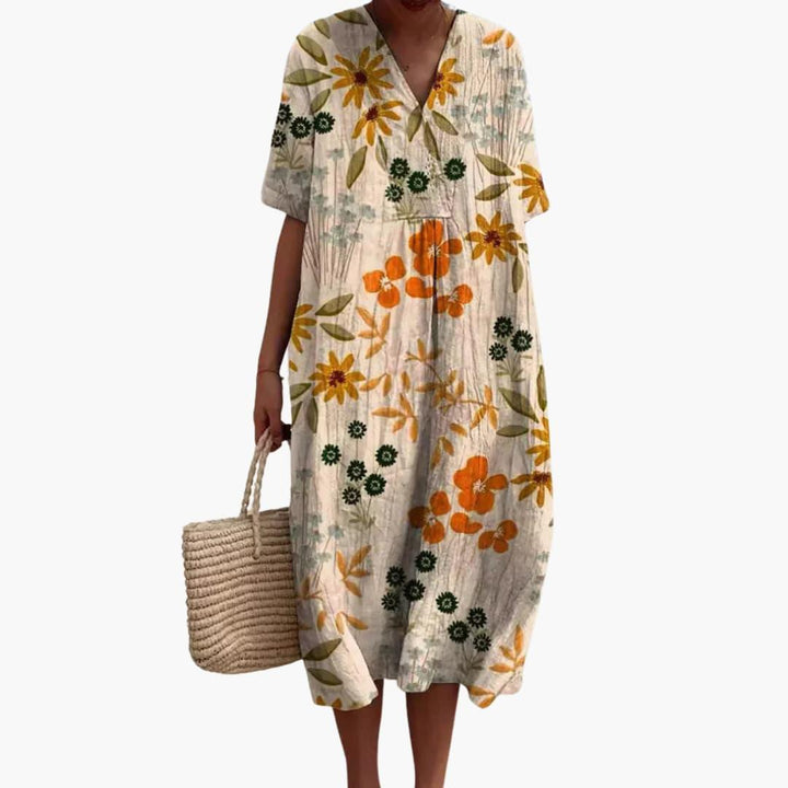 Comfortable women's floral midi dress. Features short sleeves, V-neck, oversized fit, and practical pockets.