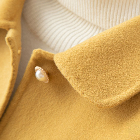 Close-up of the button closure on a women's lightweight cashmere knit jacket, showing texture